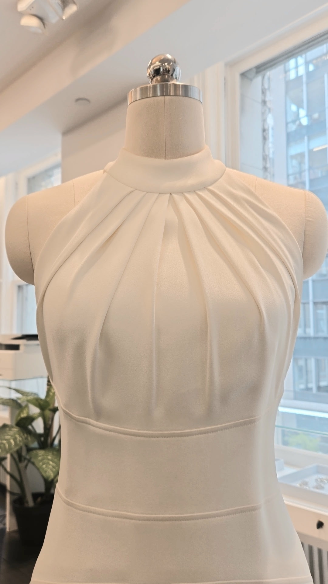Suzanne Neville Belle Wedding Dress - Simple Modern Fit and Flare Bridal Gown with Princess Seams, Halter Neck, Rouching Details in Crepe Fabric.