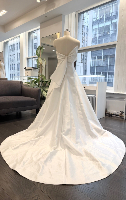 Allison Webb Baxley Wedding Dress - Snow mikado A-line gown with crescent neckline, and origami half bow, and chapel train. Optional pearl illusion halter.