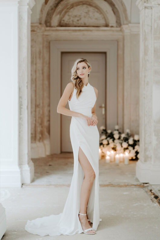 Suzanne Neville Katikies Wedding Dress - Satin crepe fit and flare dress with a slit on front, fitted bodice, draped detail, open back and high neckline