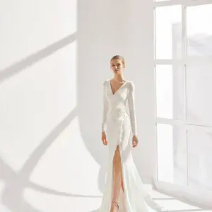 Rosa Clara Ribas Wedding Dress - A sheath-style, with a V-neckline, long sleeves, oversized floral decoration at the waist, open back and a crepe skirt