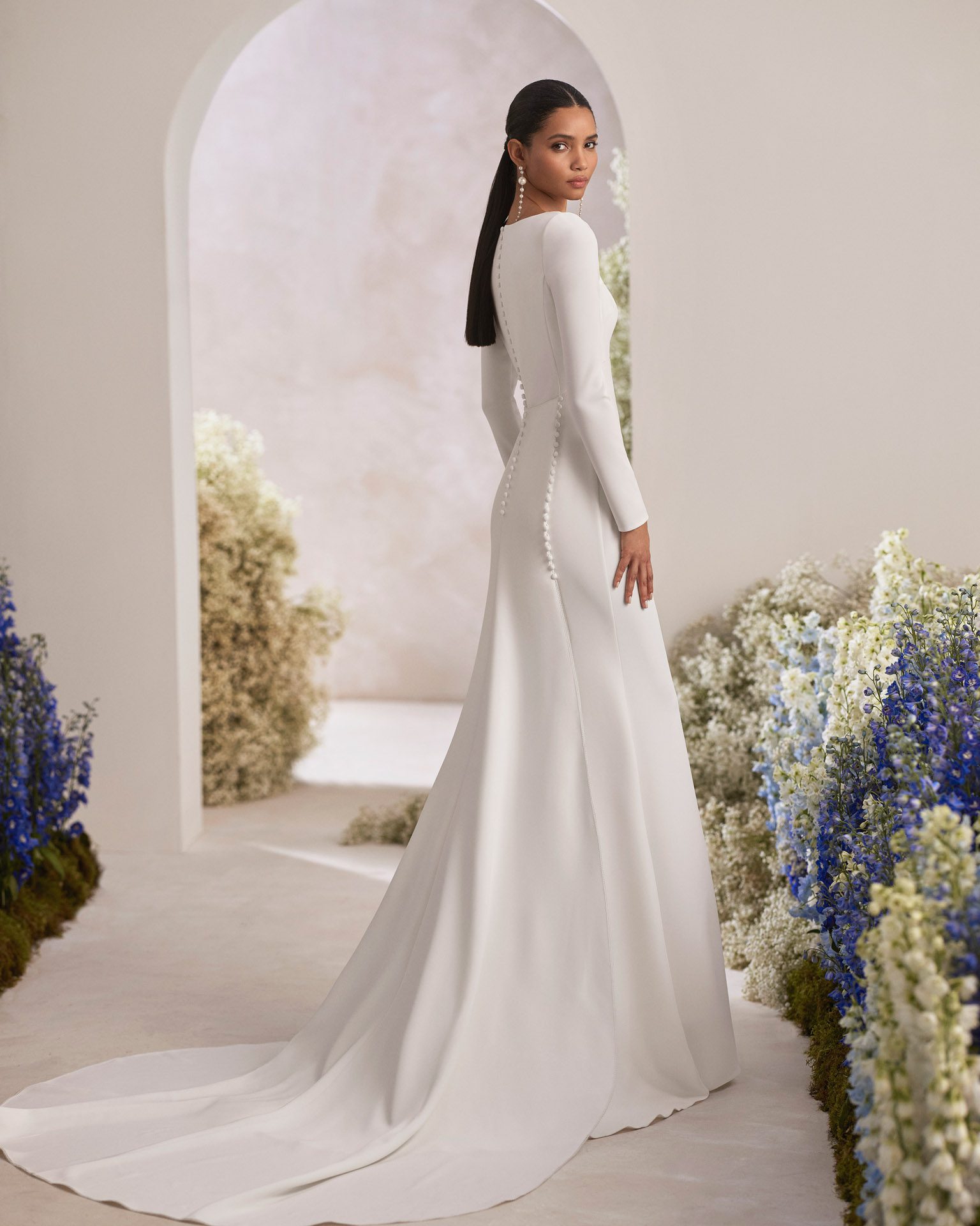 Rosa Clará Trebol Wedding Dress - Modern two-piece mermaid wedding dress made in bistretch crêpe. Showcase a square neckline, closed back and long sleeve. The cut-out embellishment, decorative buttons and detachable bistretch crêpe train complete the look.