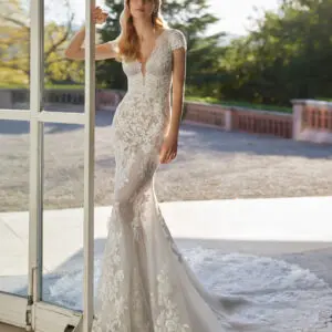 Rosa Clará Velmat Wedding Dress - Fantasy style long mermaid-style wedding dress crafted in lace with beadwork details. Featuring a V-neckline, buttoned back and short sleeve.