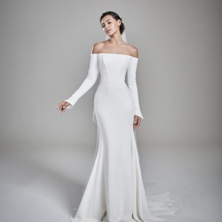 Suzanne Neville Abigail Wedding Dress - Off the shoulder, fit and flare dress with low v- back, inner corset bodice and long sleeves with flutter cuff.